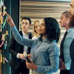 business people brainstorming putting sticky notes on glass wall